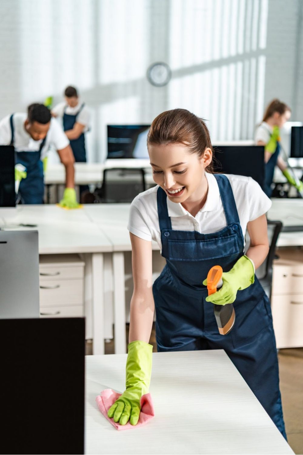 rofessional office cleaner wiping down desk at The Spotless Crew